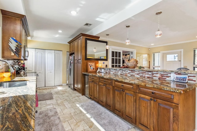 kitchen featuring stainless steel refrigerator, stone counters, sink, and pendant lighting