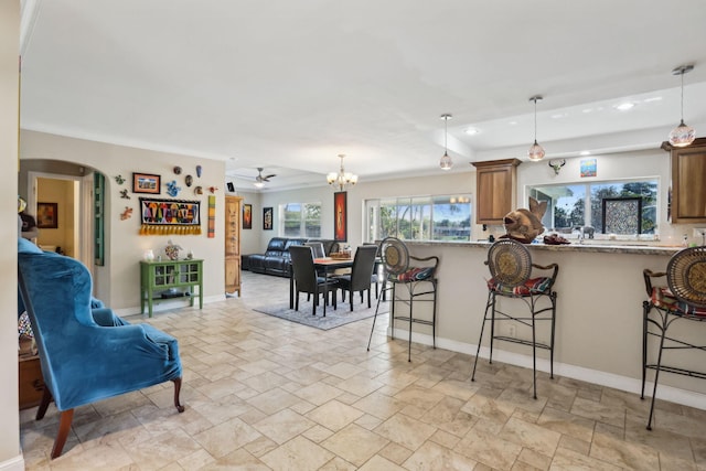 kitchen with a breakfast bar area, light stone counters, and hanging light fixtures