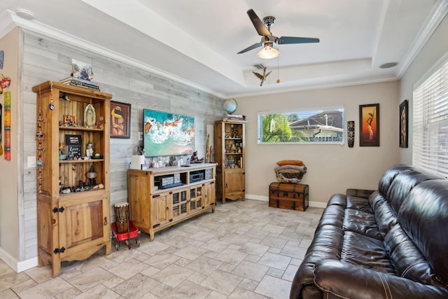 living room with a raised ceiling, plenty of natural light, and ceiling fan