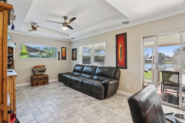 living room featuring ceiling fan, a water view, crown molding, and a tray ceiling