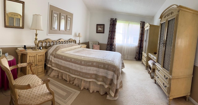 bedroom featuring a textured ceiling, light carpet, and vaulted ceiling