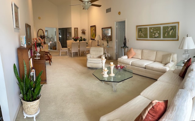 living room with ceiling fan, carpet floors, and a high ceiling