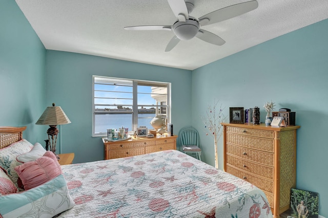 bedroom featuring a textured ceiling, a water view, and ceiling fan