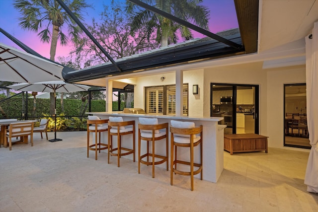 patio terrace at dusk with a bar and a lanai