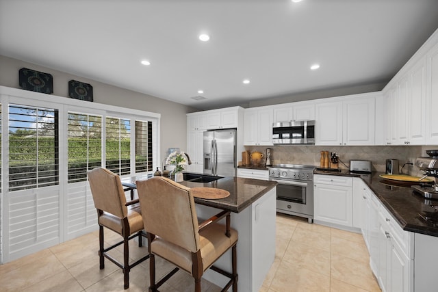 kitchen with stainless steel appliances, decorative backsplash, and white cabinetry