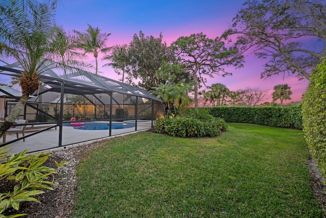 yard at dusk with a patio and glass enclosure