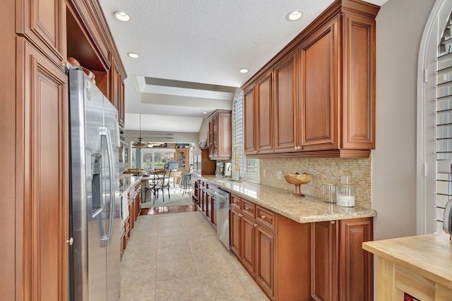 kitchen with sink, ceiling fan, light stone countertops, ornamental molding, and appliances with stainless steel finishes