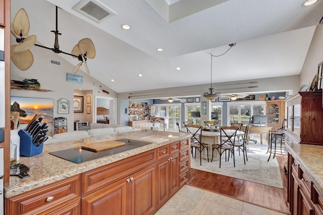 kitchen featuring light stone countertops, ceiling fan, a textured ceiling, black electric stovetop, and light tile patterned flooring