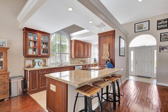 kitchen featuring a center island, black electric stovetop, sink, hardwood / wood-style flooring, and tasteful backsplash