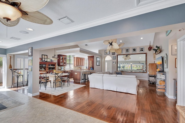 tiled living room featuring a wealth of natural light, ornamental molding, and ceiling fan