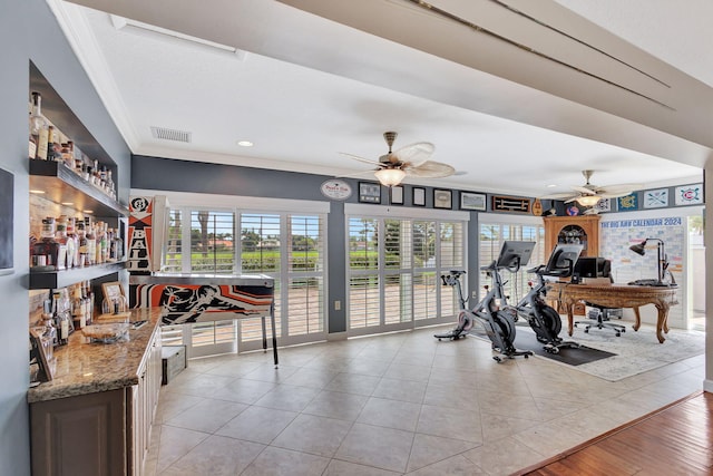 exercise room with light tile patterned floors, ceiling fan, and crown molding