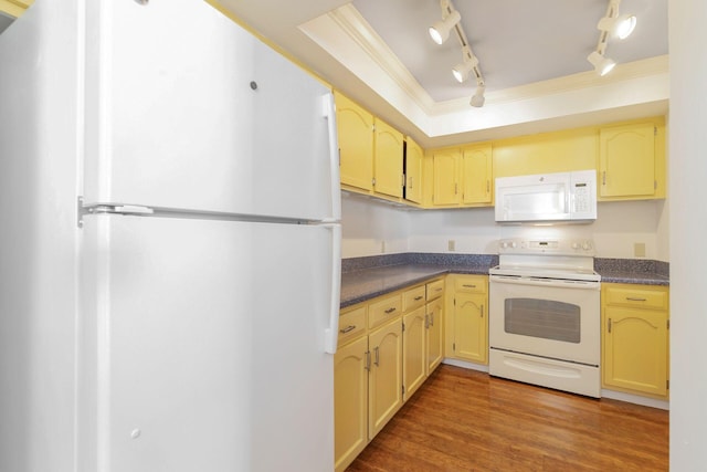 kitchen with a raised ceiling, crown molding, dark wood-type flooring, and white appliances