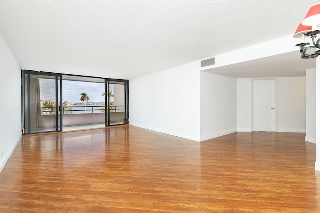 empty room with hardwood / wood-style floors, floor to ceiling windows, and a textured ceiling