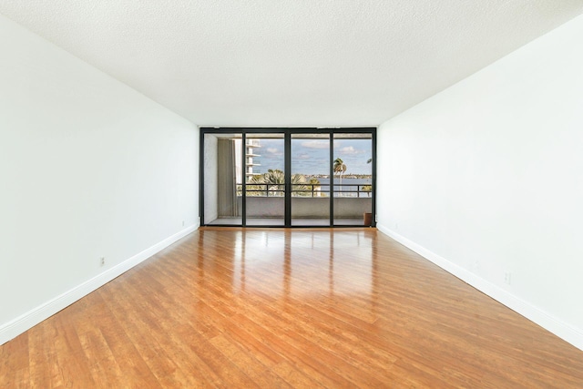 spare room with floor to ceiling windows, light hardwood / wood-style floors, and a textured ceiling