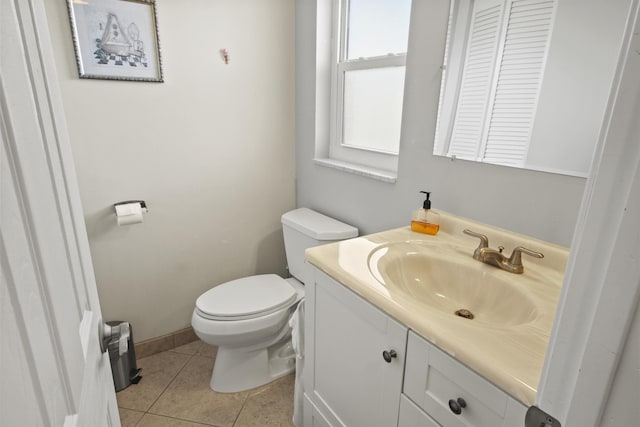 half bathroom with tile patterned flooring, toilet, vanity, and baseboards