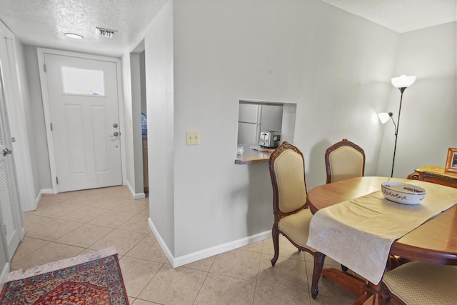 dining room featuring light tile patterned floors, visible vents, baseboards, and a textured ceiling