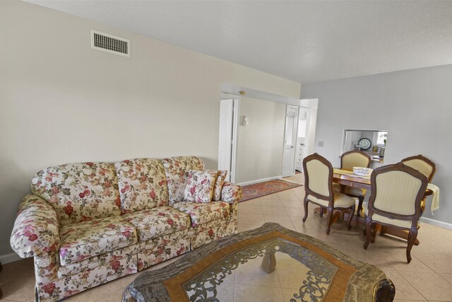 living room with tile patterned floors, visible vents, and baseboards