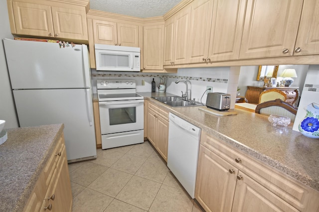 kitchen with white appliances, light brown cabinets, and a sink