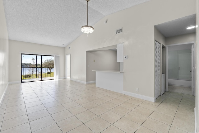 tiled spare room with a textured ceiling, a water view, and lofted ceiling