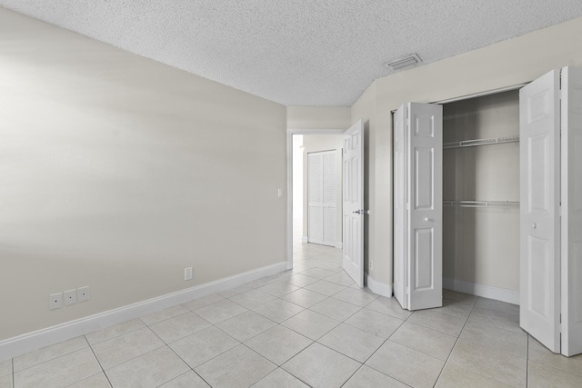 unfurnished bedroom featuring a textured ceiling, a closet, and light tile patterned flooring