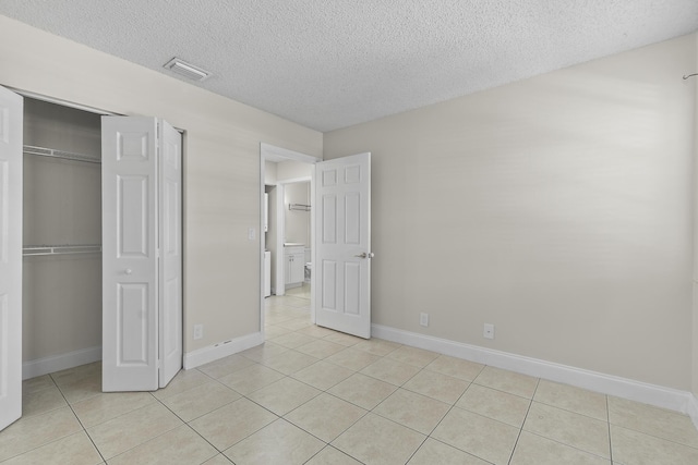 unfurnished bedroom with light tile patterned floors, a textured ceiling, and a closet