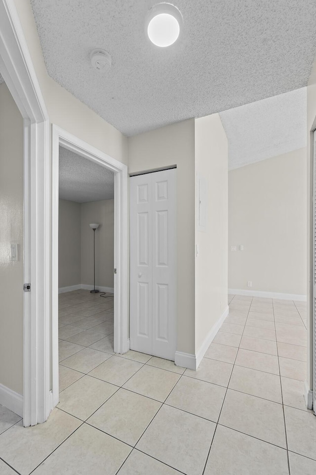 hall with light tile patterned flooring and a textured ceiling