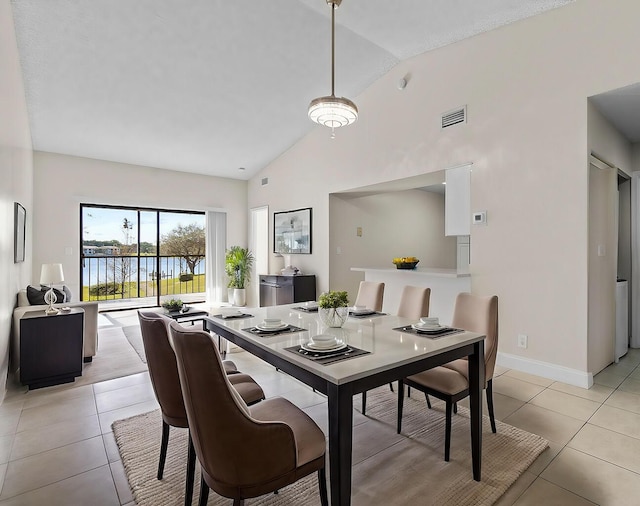 dining area with lofted ceiling, a water view, and light tile patterned floors