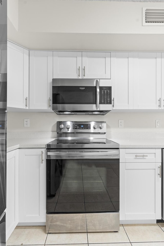 kitchen featuring white cabinets, appliances with stainless steel finishes, and light tile patterned floors