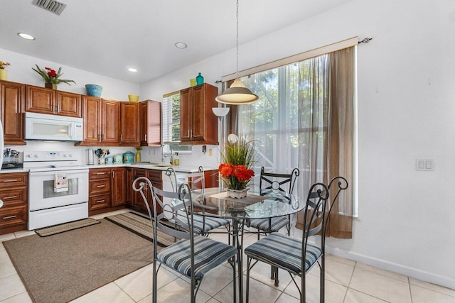 kitchen with sink, light tile patterned flooring, pendant lighting, and range