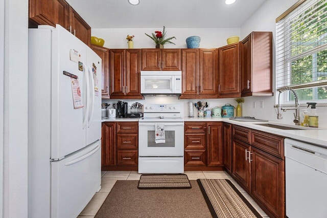 kitchen featuring light tile patterned floors, white appliances, and sink