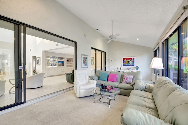 living room featuring ceiling fan, light colored carpet, a textured ceiling, and vaulted ceiling