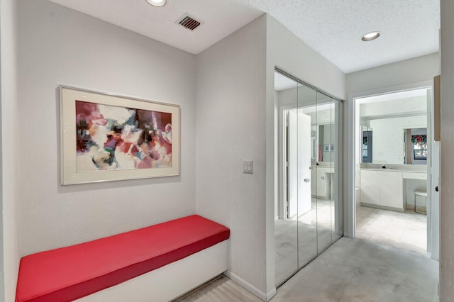 hallway with a textured ceiling and light carpet