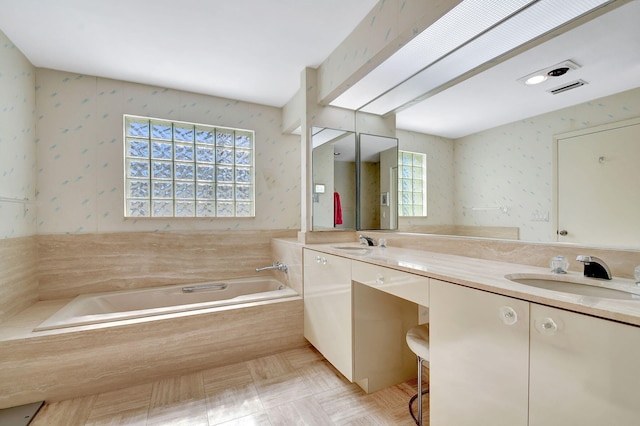 bathroom featuring tiled tub and vanity