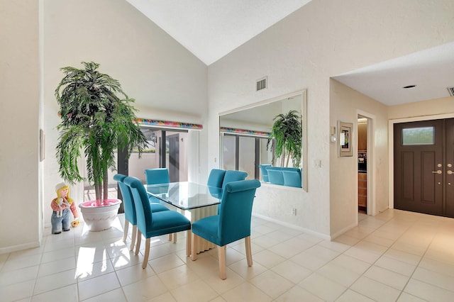 dining room with light tile patterned floors and high vaulted ceiling