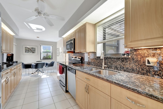 kitchen featuring appliances with stainless steel finishes, light tile patterned floors, light brown cabinetry, and sink