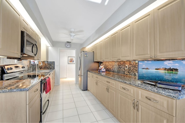 kitchen featuring ceiling fan, sink, stainless steel appliances, dark stone counters, and light tile patterned flooring