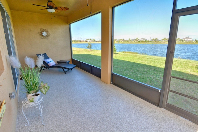 sunroom with ceiling fan and a water view