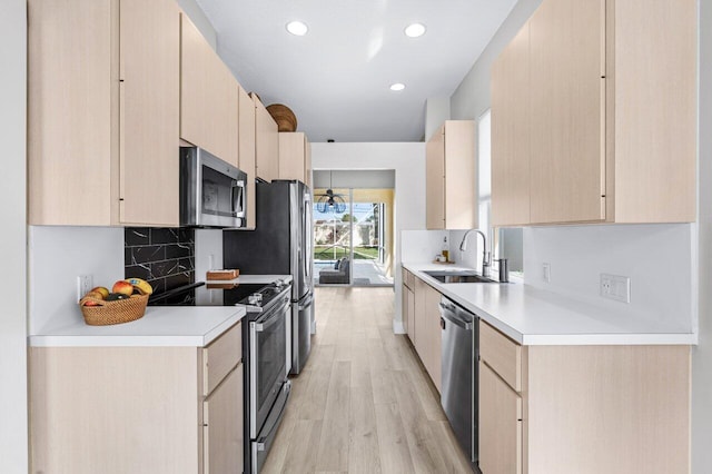 kitchen featuring light brown cabinetry, light wood-type flooring, backsplash, stainless steel appliances, and sink