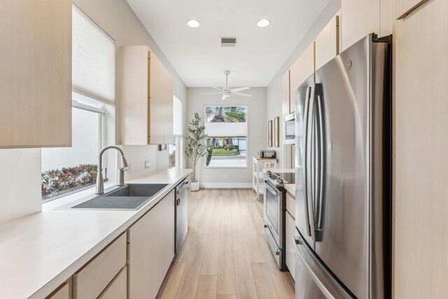 kitchen featuring sink, light brown cabinets, tasteful backsplash, appliances with stainless steel finishes, and light wood-type flooring