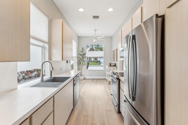 kitchen featuring ceiling fan, appliances with stainless steel finishes, sink, and light wood-type flooring