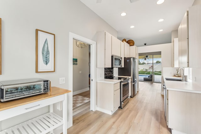 kitchen with sink, white cabinetry, tasteful backsplash, light hardwood / wood-style flooring, and appliances with stainless steel finishes