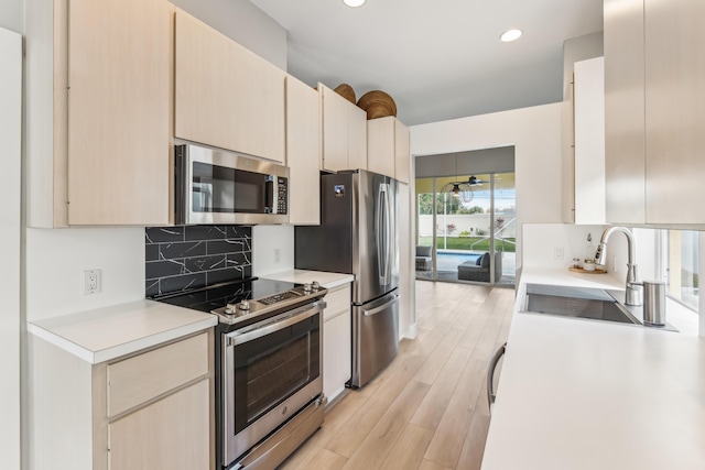 kitchen featuring stainless steel appliances, sink, light hardwood / wood-style floors, and decorative backsplash