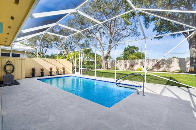 view of pool with a patio area, a lawn, and glass enclosure