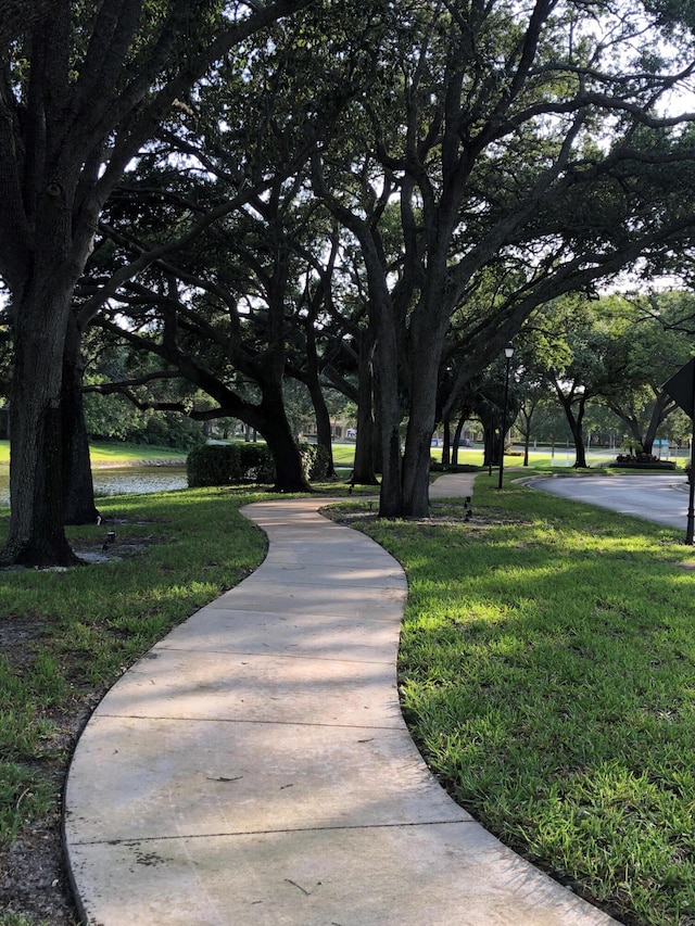 surrounding community with a water view and a lawn