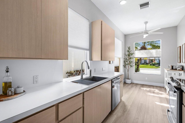 kitchen with appliances with stainless steel finishes, light wood-type flooring, light brown cabinetry, ceiling fan, and sink