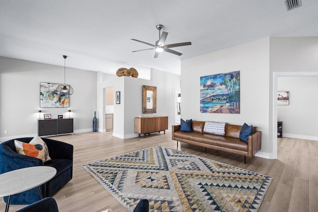 living room with hardwood / wood-style floors, a textured ceiling, and ceiling fan