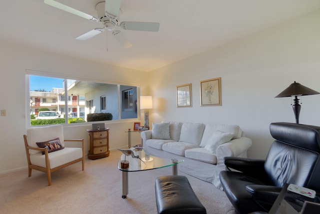 living area featuring baseboards, a ceiling fan, and light colored carpet