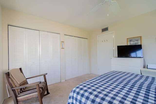 bedroom with multiple closets, ceiling fan, and light carpet