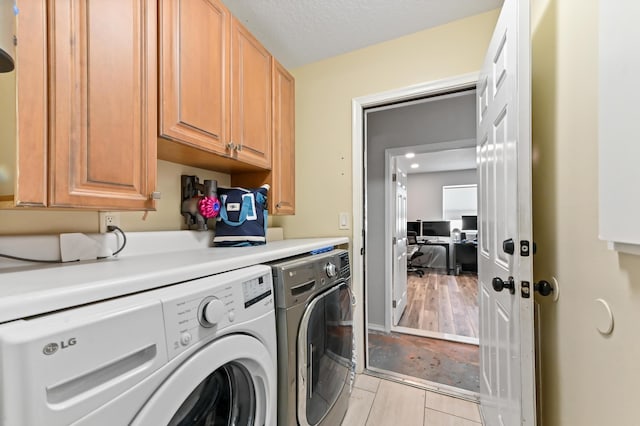 washroom featuring washer and dryer, cabinets, and a textured ceiling