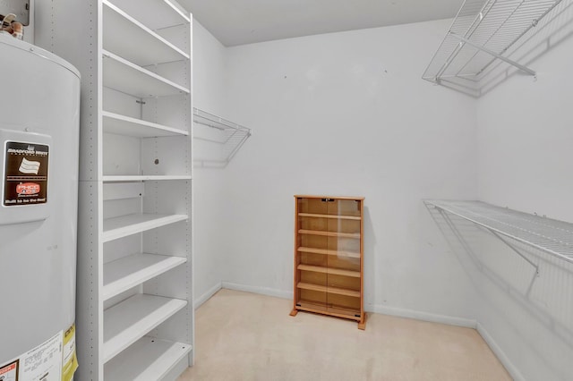 walk in closet featuring water heater and light colored carpet